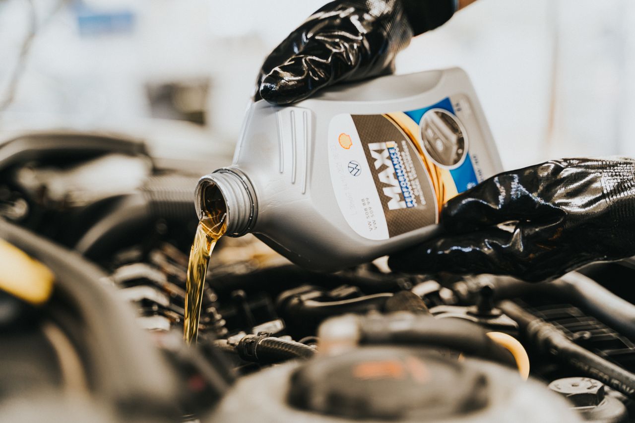 Hello world! Close-up of a mechanic pouring engine oil into a car engine, highlighting maintenance work.