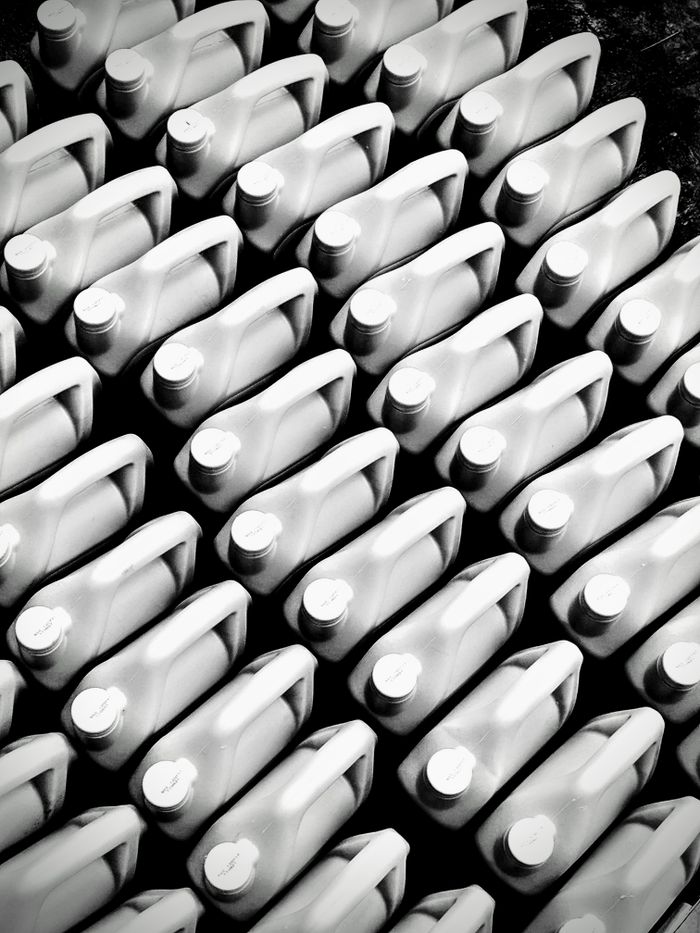 Services Patterned arrangement of plastic bottles viewed from above in black and white.